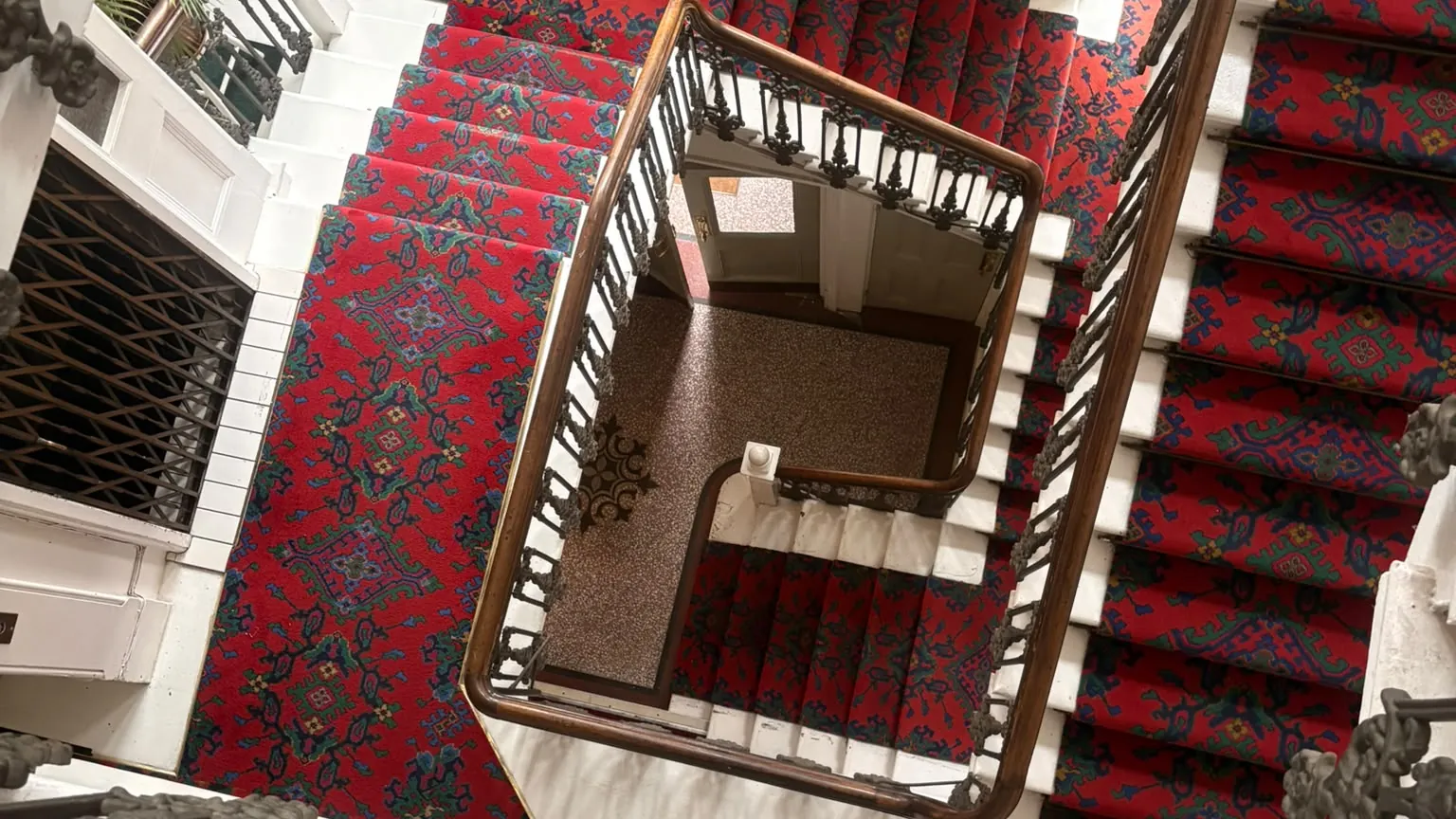 A red-carpeted period staircase with iron balusters, on a Wolves Removals flat move in Hove